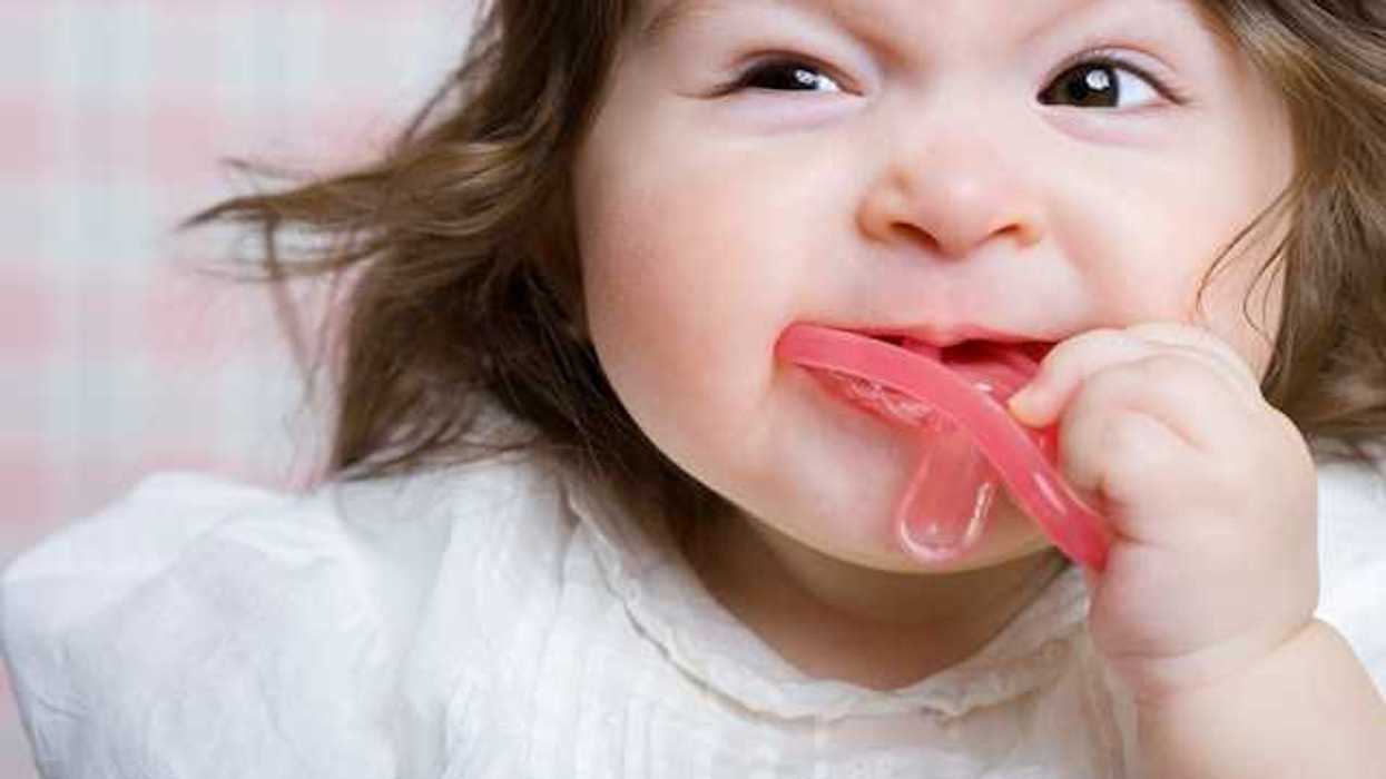 A toddler girl with a pink pacifier in her mouth