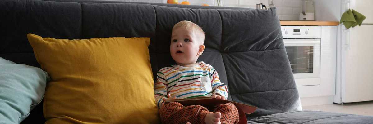 A toddler sits on a couch.