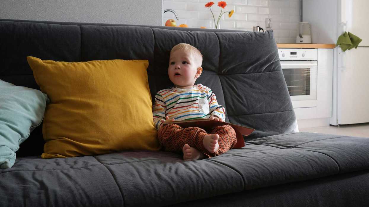 A toddler sits on a couch