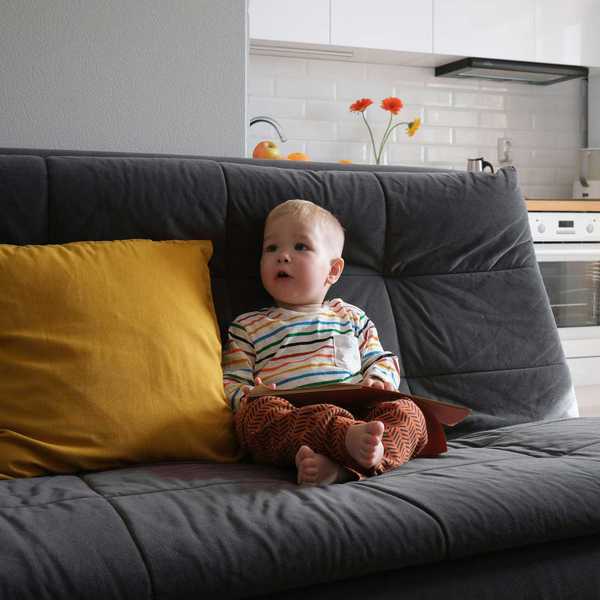 A toddler sits on a couch.