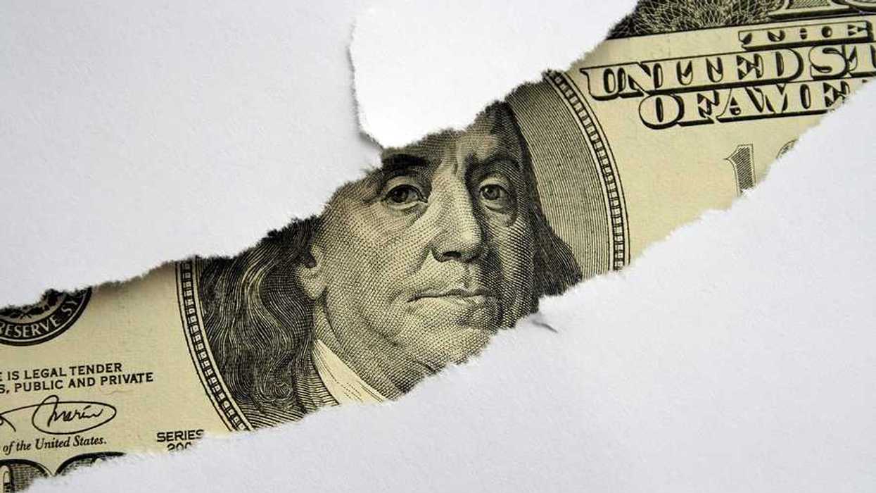 A torn white piece of paper with a $100 bill shown behind it