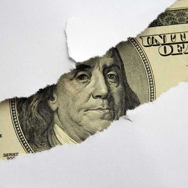 A torn white piece of paper with a $100 bill shown behind it