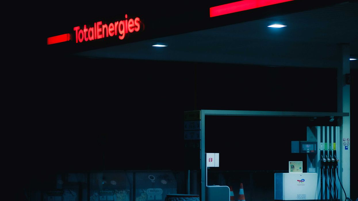 a TotalEnergies gas station illuminated in red letters at night.