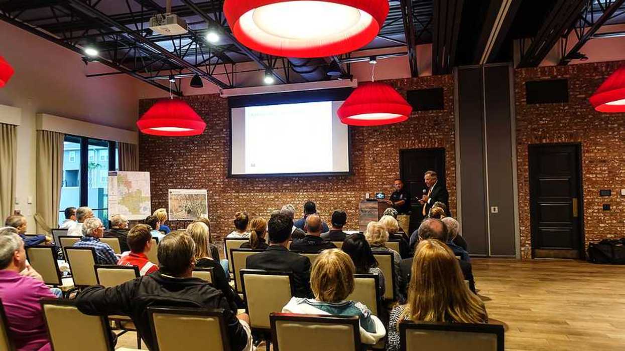 A town hall meeting with people sitting in chairs listening to a presentation