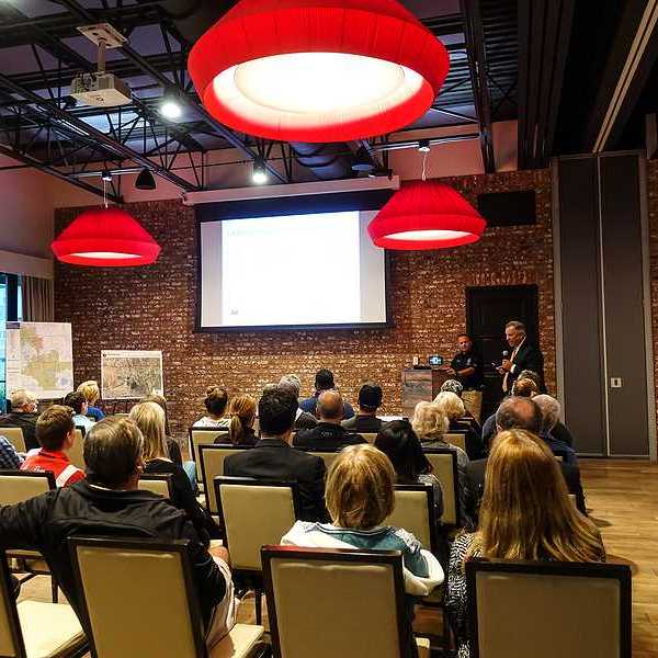 A town hall meeting with people sitting in chairs listening to a presentation