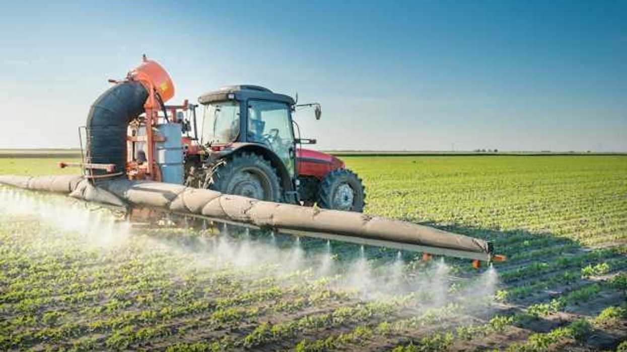 A tractor applies pesticides to a farm field