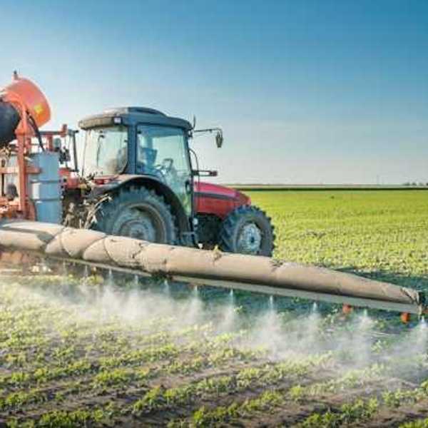 A tractor applies pesticides to a farm field