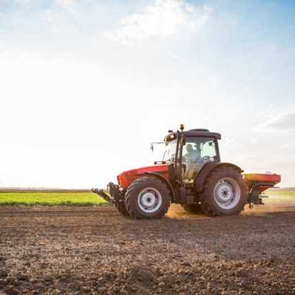 A tractor applying fertilizer on a brown field
