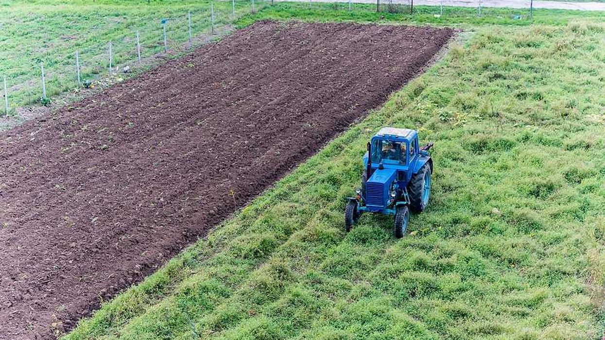 A tractor applying fertilizer sludge to a farm field