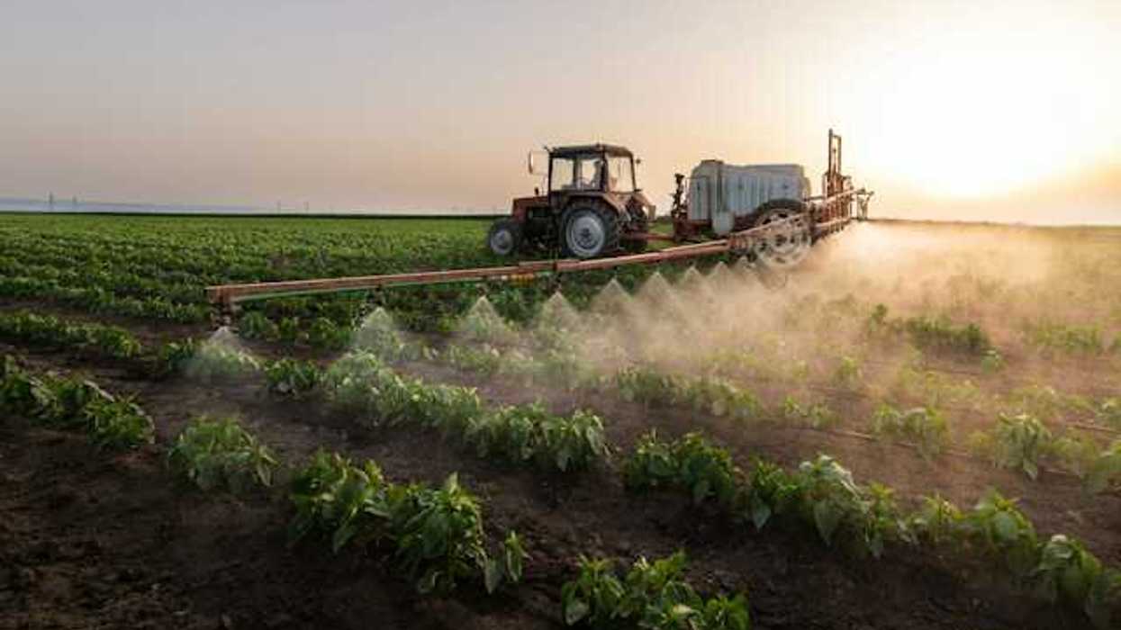 A tractor applying pesticides on a farm field