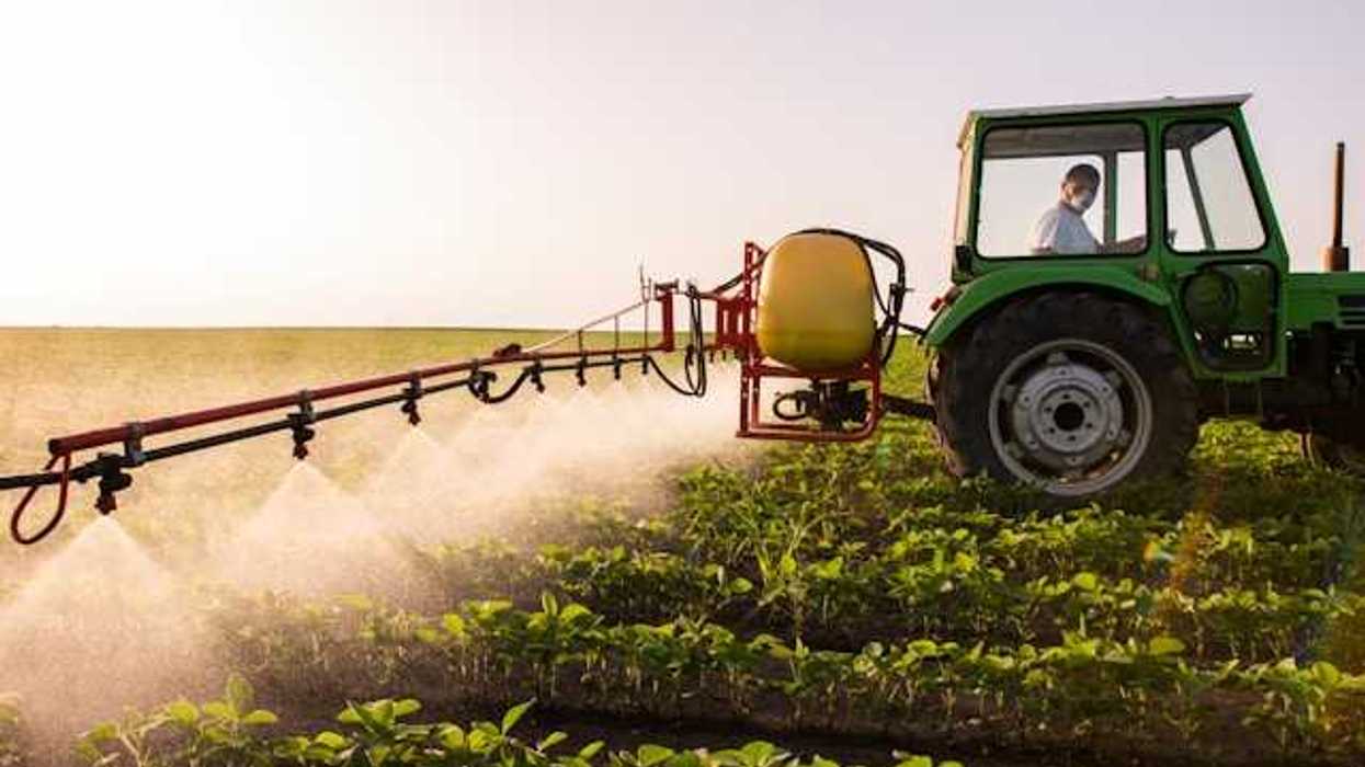 A tractor applying pesticides to a farm field