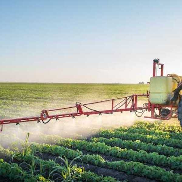A tractor applying pesticides to a green farm field