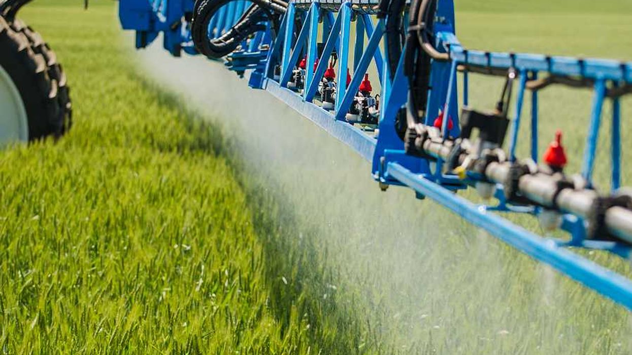 A tractor arm spraying pesticides on a field
