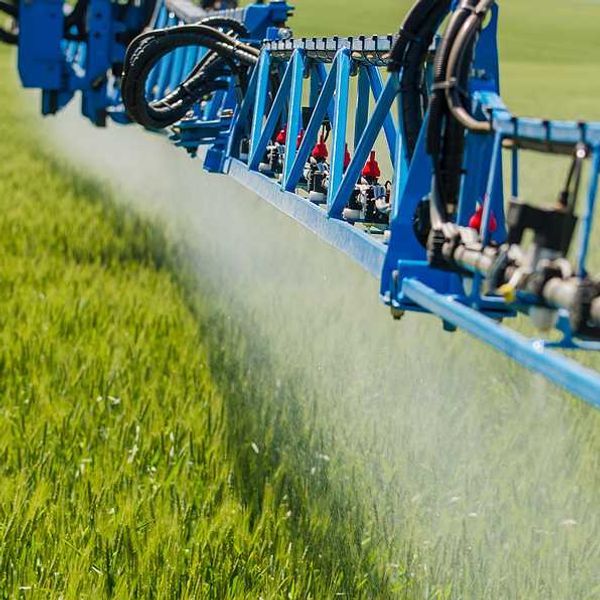 A tractor arm spraying pesticides on a field