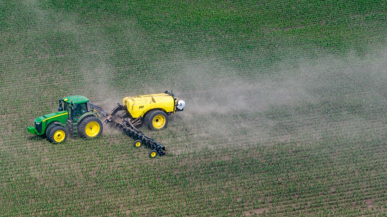 a tractor in a field spraying agrochemicals.