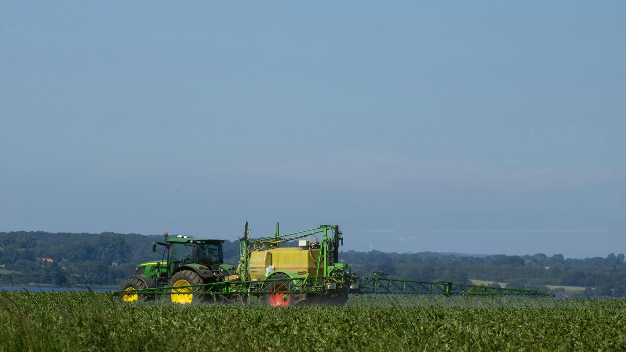 a tractor in a field spraying pesticides.