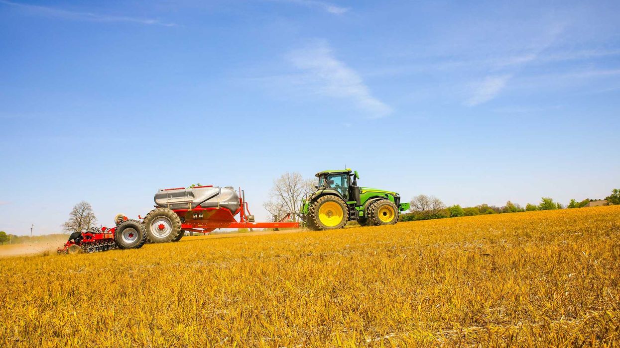 a tractor pulling a trailer behind it across a field