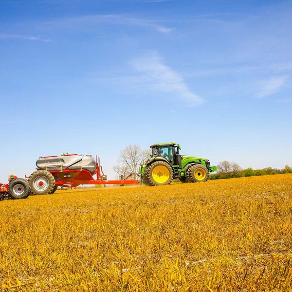 a tractor pulling a trailer behind it across a field
