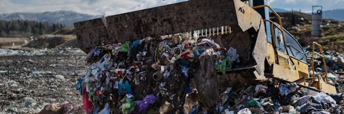 A tractor pushing trash into a pile in a landfill.