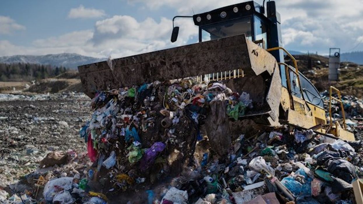A tractor pushing trash into a pile in a landfill.