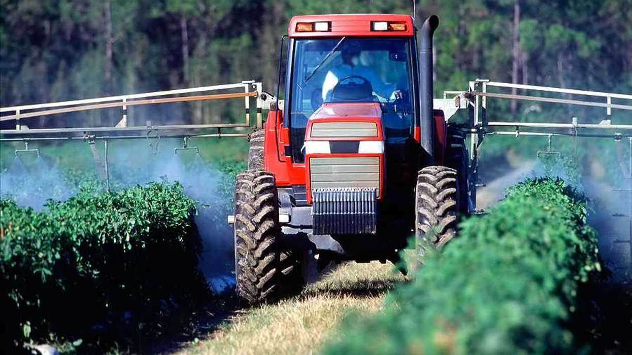 A tractor spraying crops with insecticide