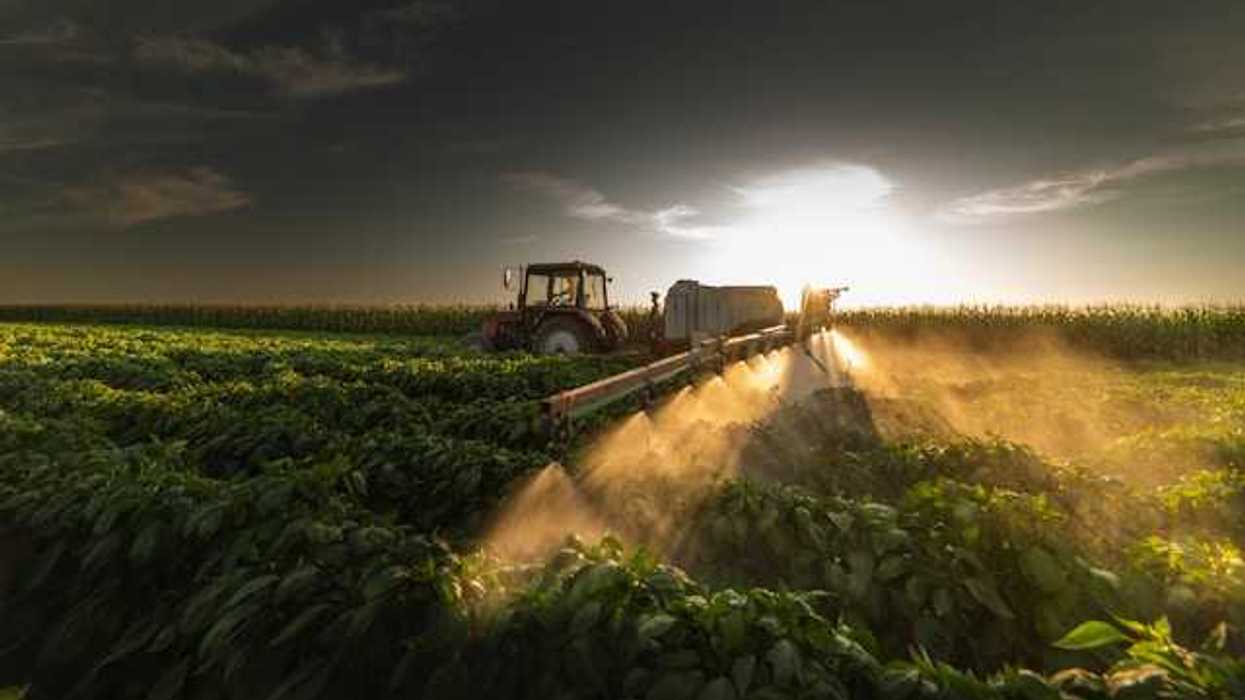 A tractor spraying pesticides on a farm field