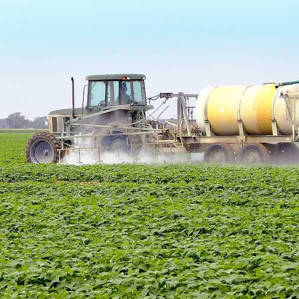 A tractor spraying pesticides on a farm field