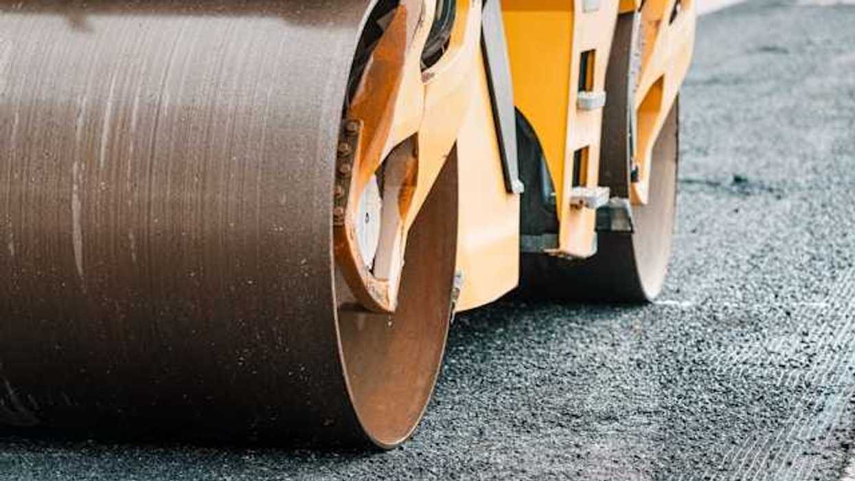 A truck laying down and flattening asphalt on a new road