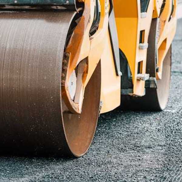 A truck laying down and flattening asphalt on a new road