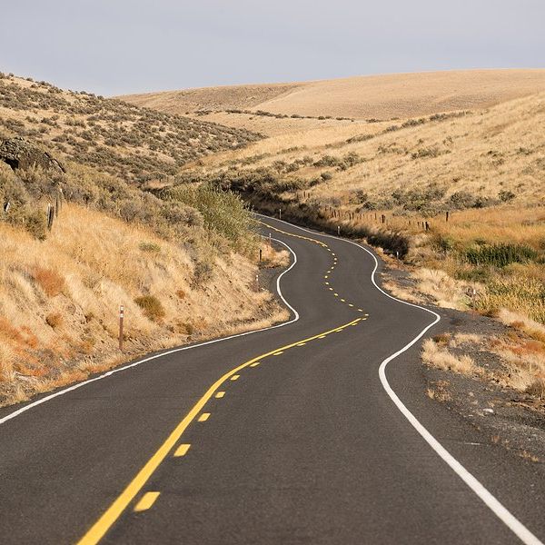 A two lane highway winding between dry hills
