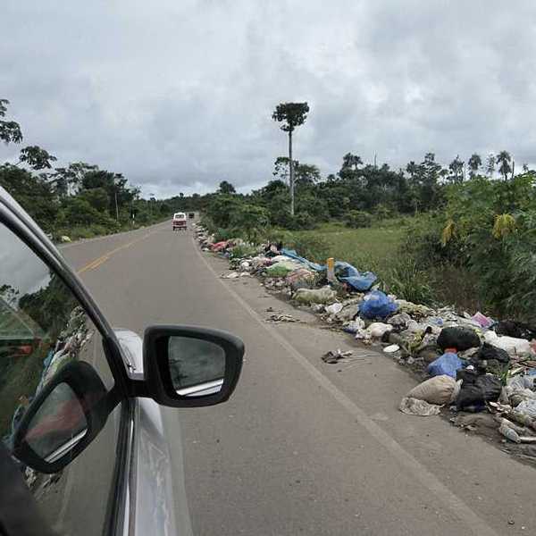 A view from a vehicle of garbage on the side of the road in the Amazon