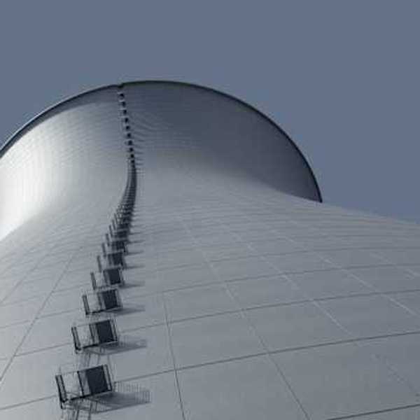 A view from below of a power cooling tower against a blue sky