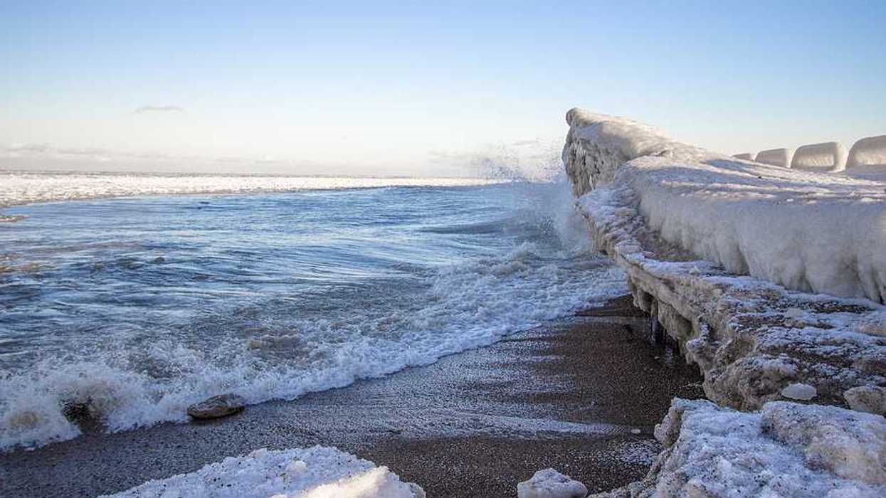 A view of a beach with ice built up on the shore and in the water