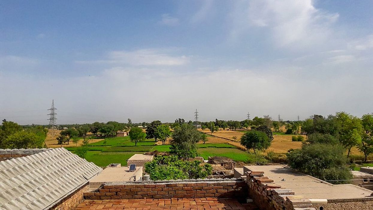A view of a brick rooftop in with green fields and electric towers in the background