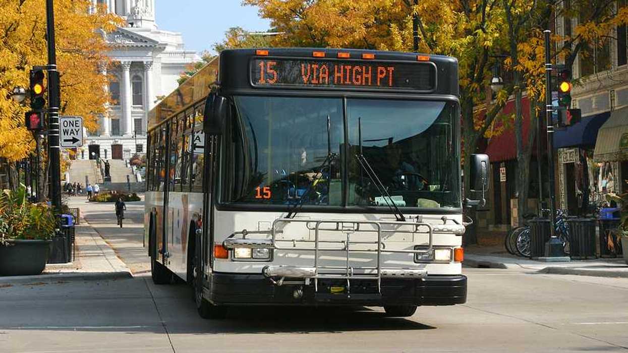 A view of a bus driving down a Madison, WI street with the capitol building in the background