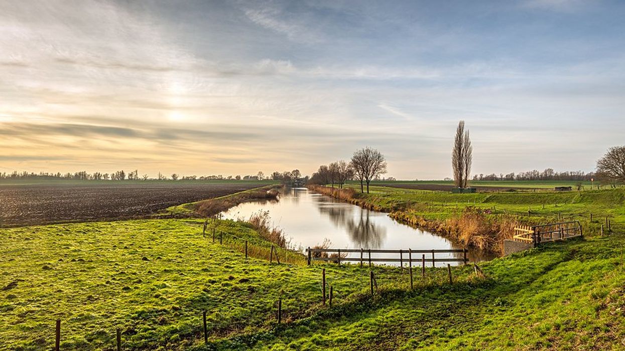 A view of a canal surrounded by farm fields