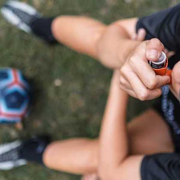 A view of a child on a soccer field with an asthma inhaler