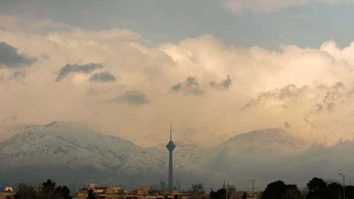 A view of a city mineret with snowy mountains in the background