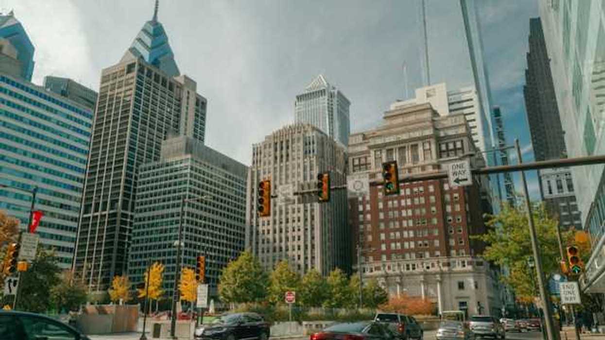 A view of a city street with tall buildings and cars driving on the street