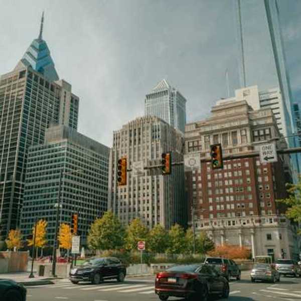 A view of a city street with tall buildings and cars driving on the street