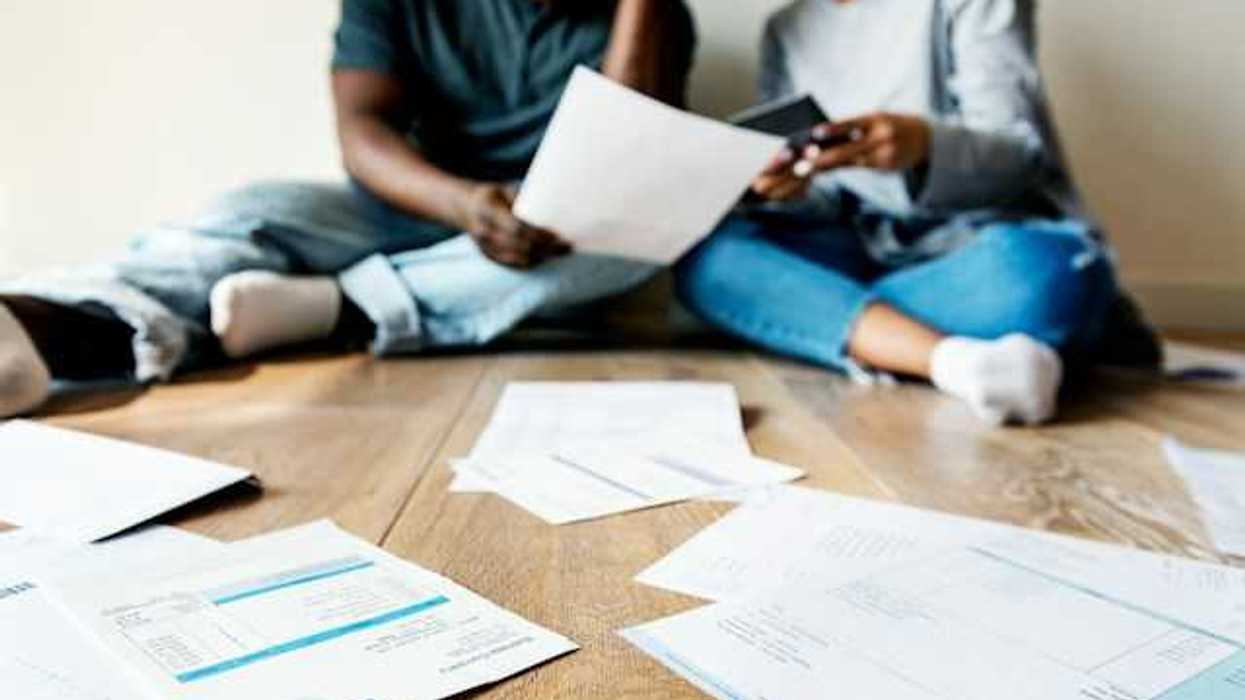 A view of a couple sitting on the floor looking through bills