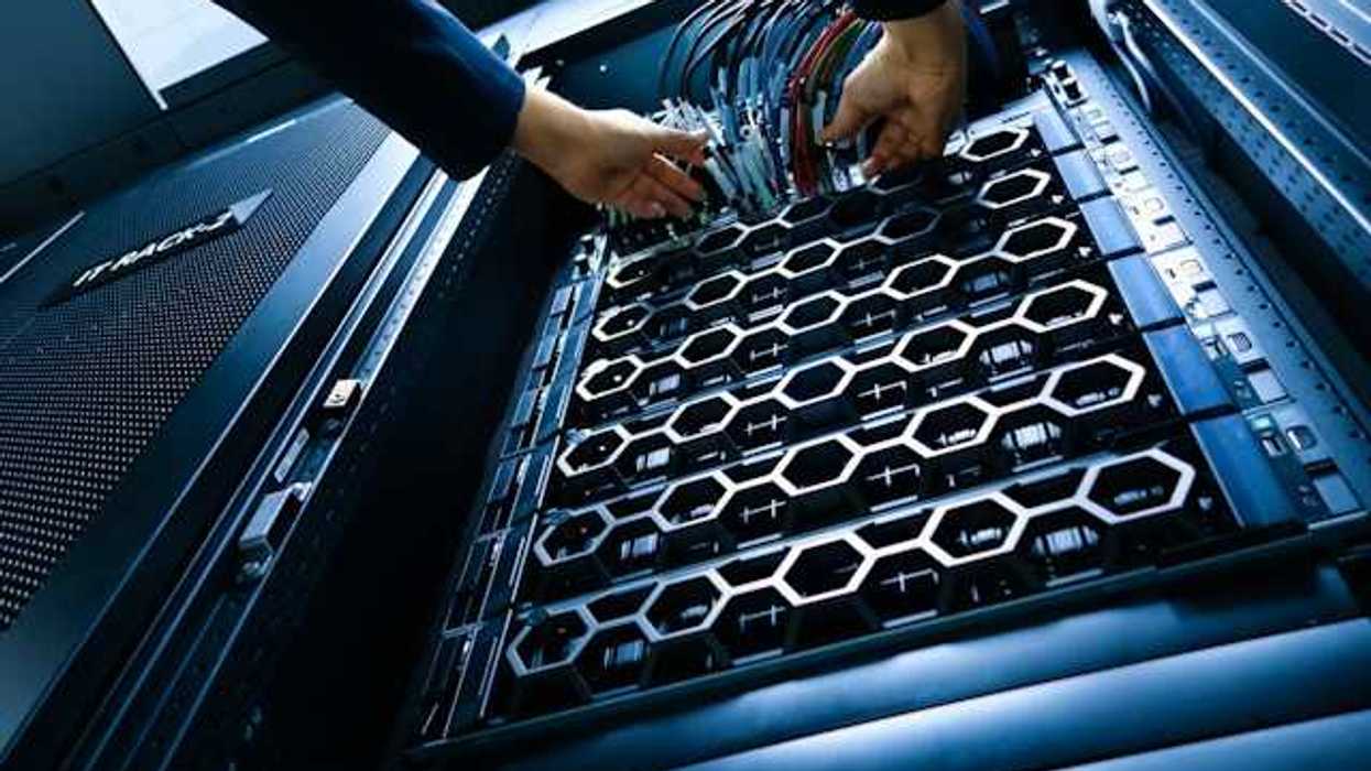 A view of a data server with a person arranging multicolored wires
