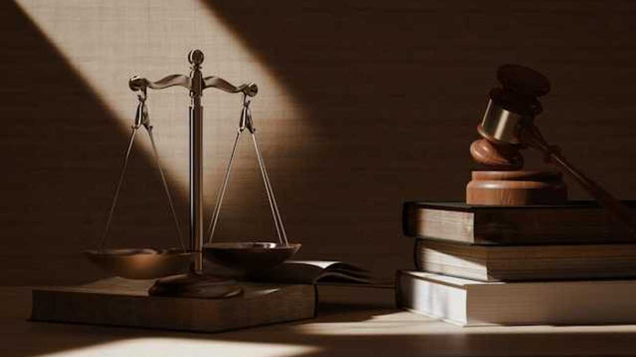 A view of a desk with the scales of justice, law books, and a wooden gavel