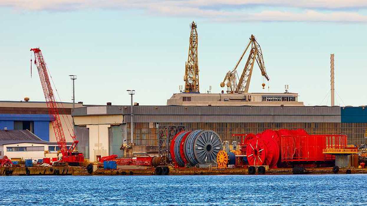 A view of a dock with giant spools of cable and cranes
