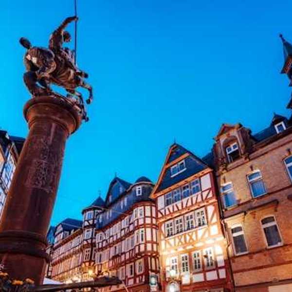 A view of a European square with half-timbered houses and a status of a man on a horse