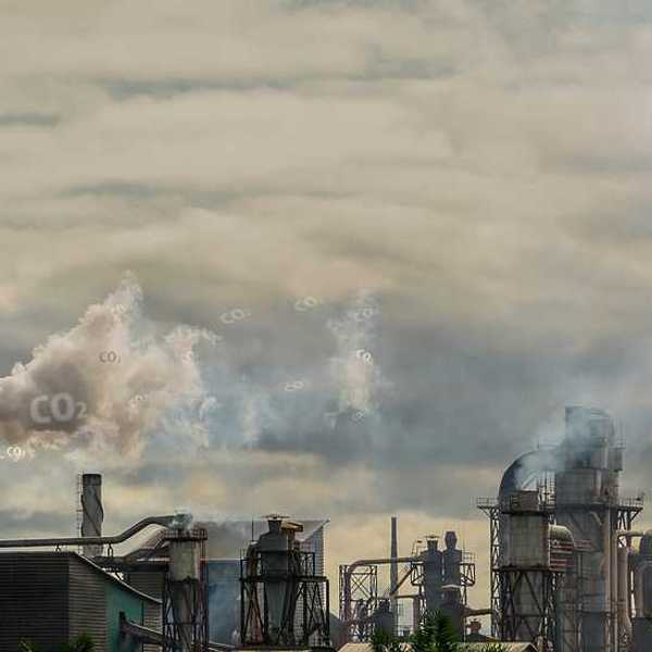 A view of a factory with smoke emitting from the smokestacks into a gray sky