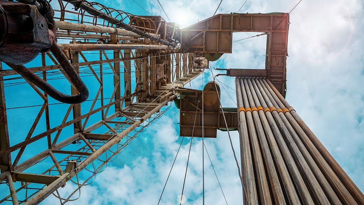 A view of a fracking tower from below against a cloudy sky