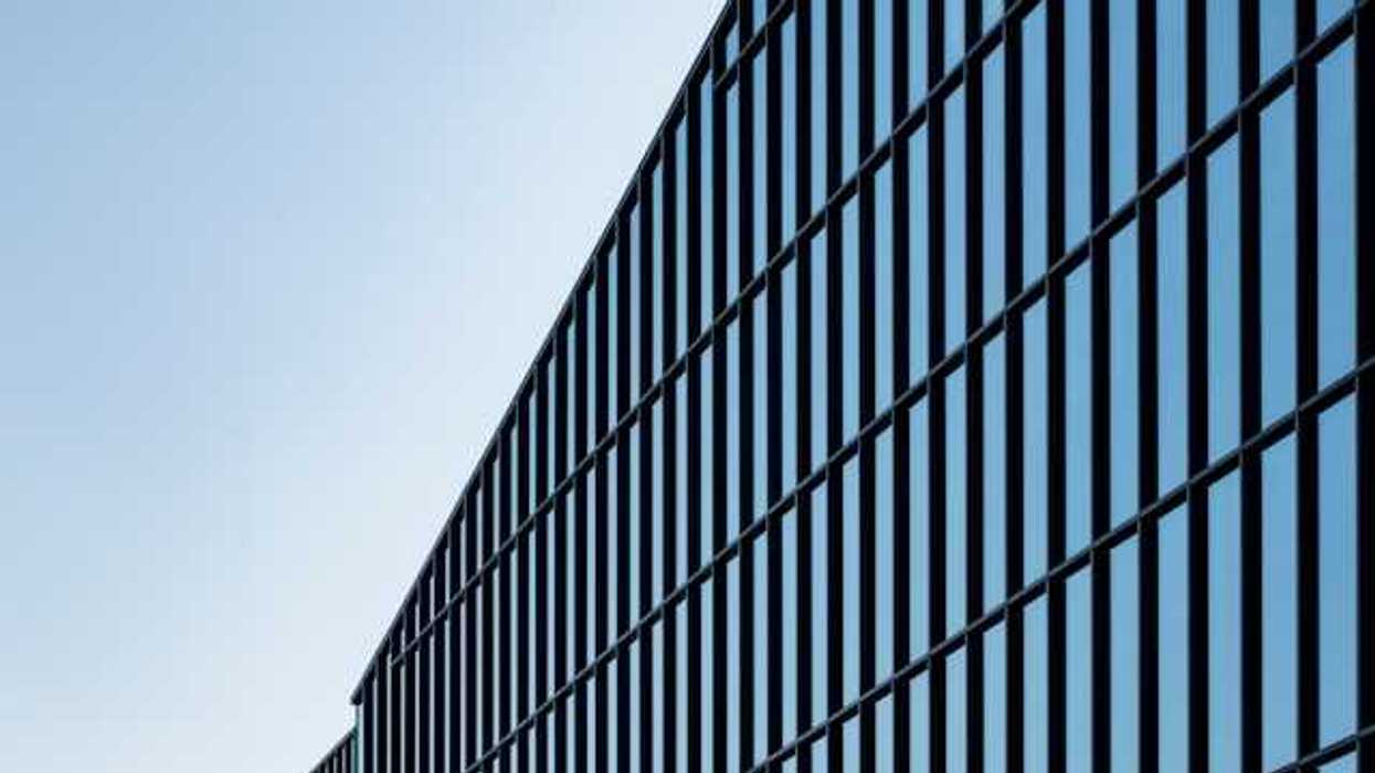 A view of a glass office building with blue sky behind it