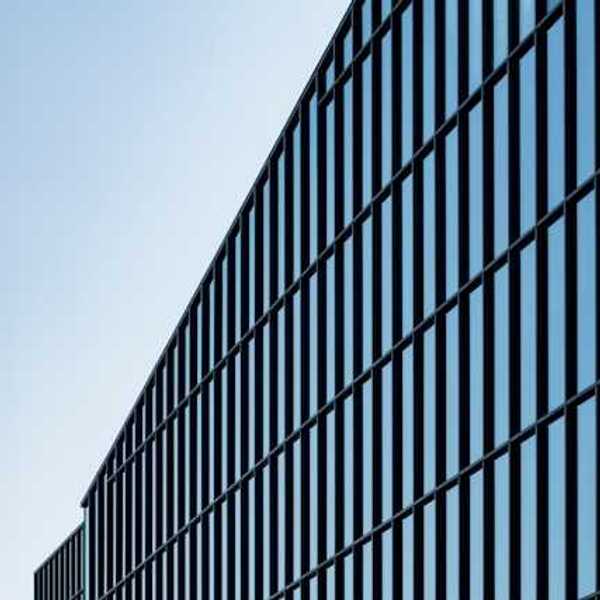 A view of a glass office building with blue sky behind it