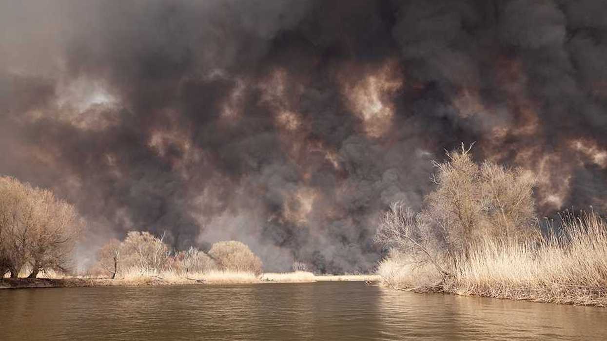 A view of a lake with billowing wildfire smoke in the background